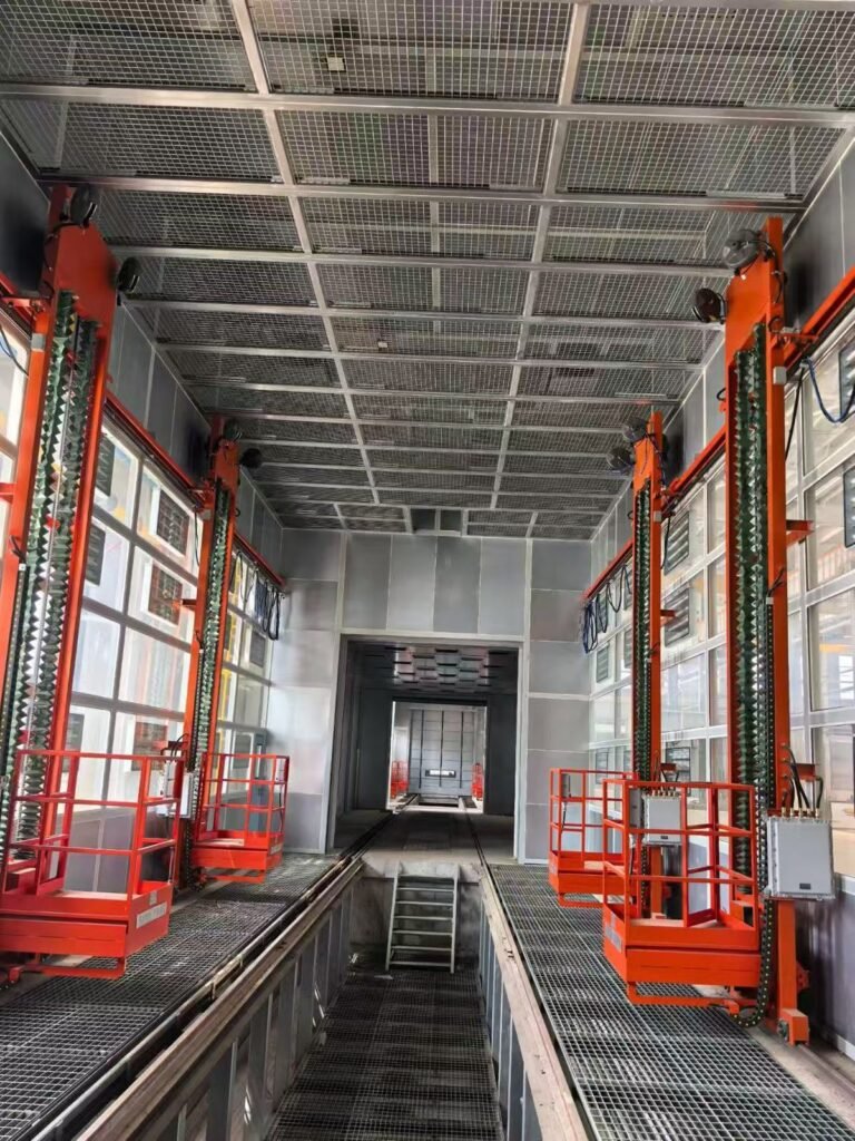 İki motorlu operatör kaldırma platformu ve ızgara zeminli bir konteyner püskürtme kabininin içi