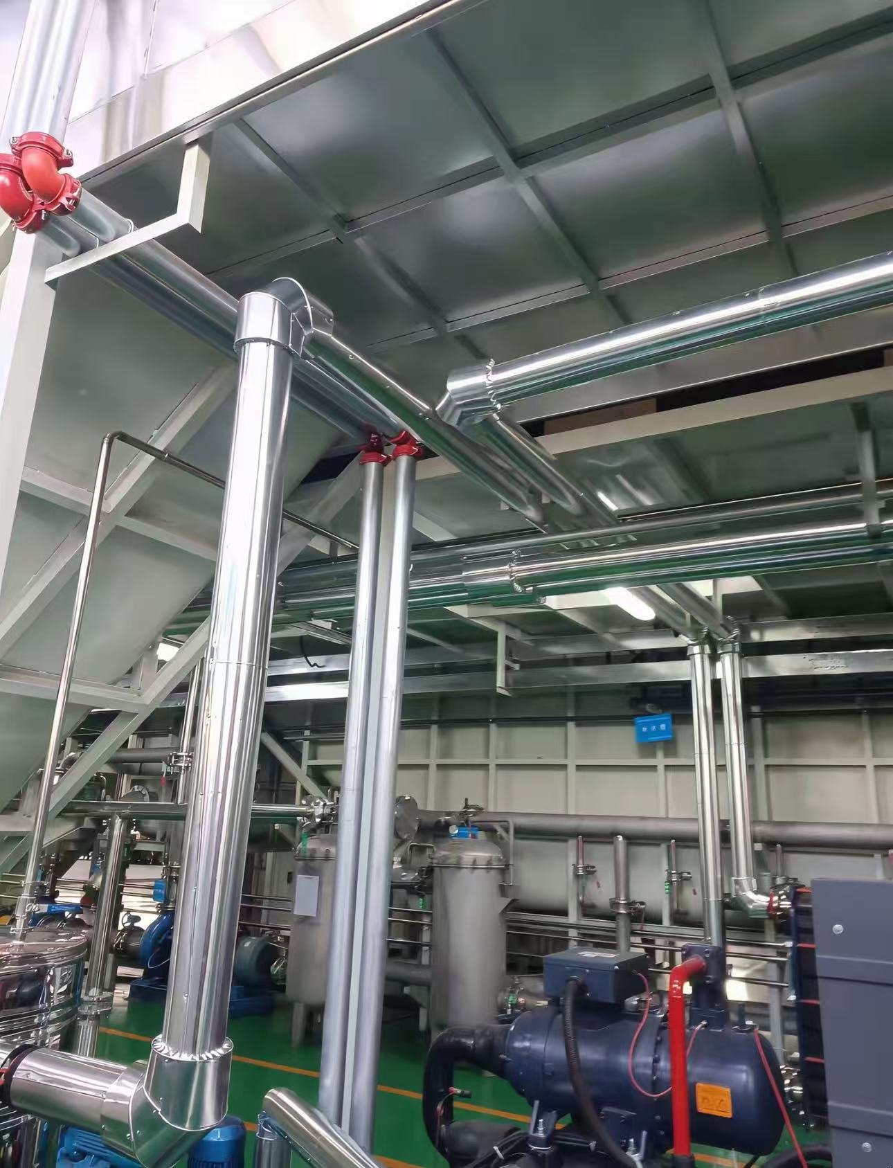Isolierte Edelstahlrohrleitungen über einem Kühlaggregat und Umwälzpumpen an einer elektrophoretischen Beschichtungslinie
