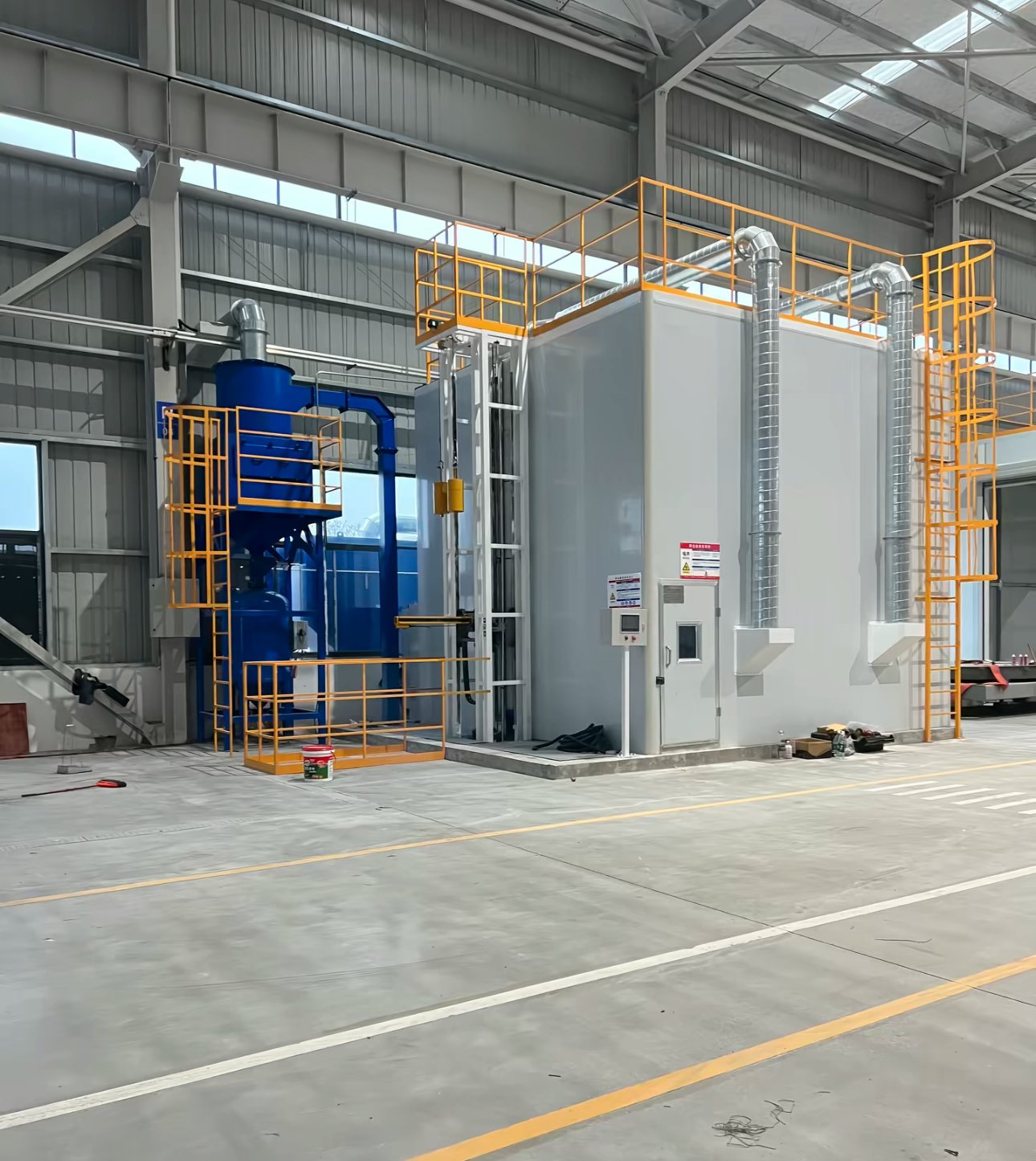Enclosed rooms of a blasting and painting line with control panel, personnel door, spiral exhaust ducts and roof platforms
